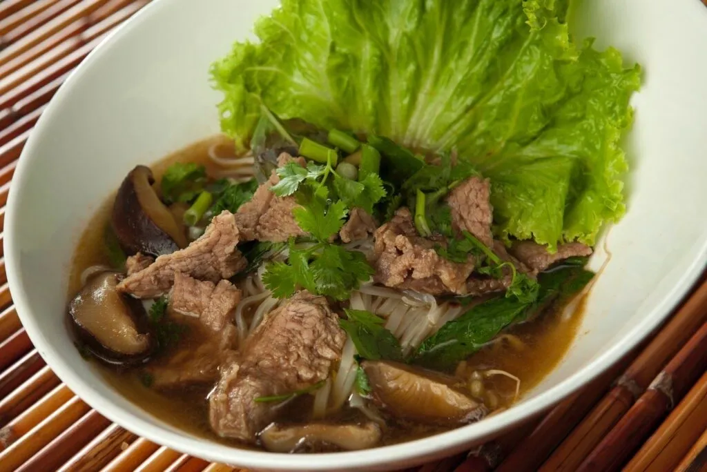 A bowl of meat and vegetables with lettuce.