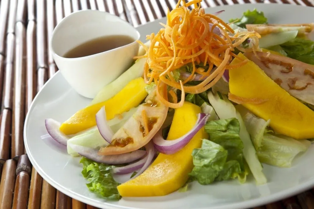 A plate of salad with dressing on the side.