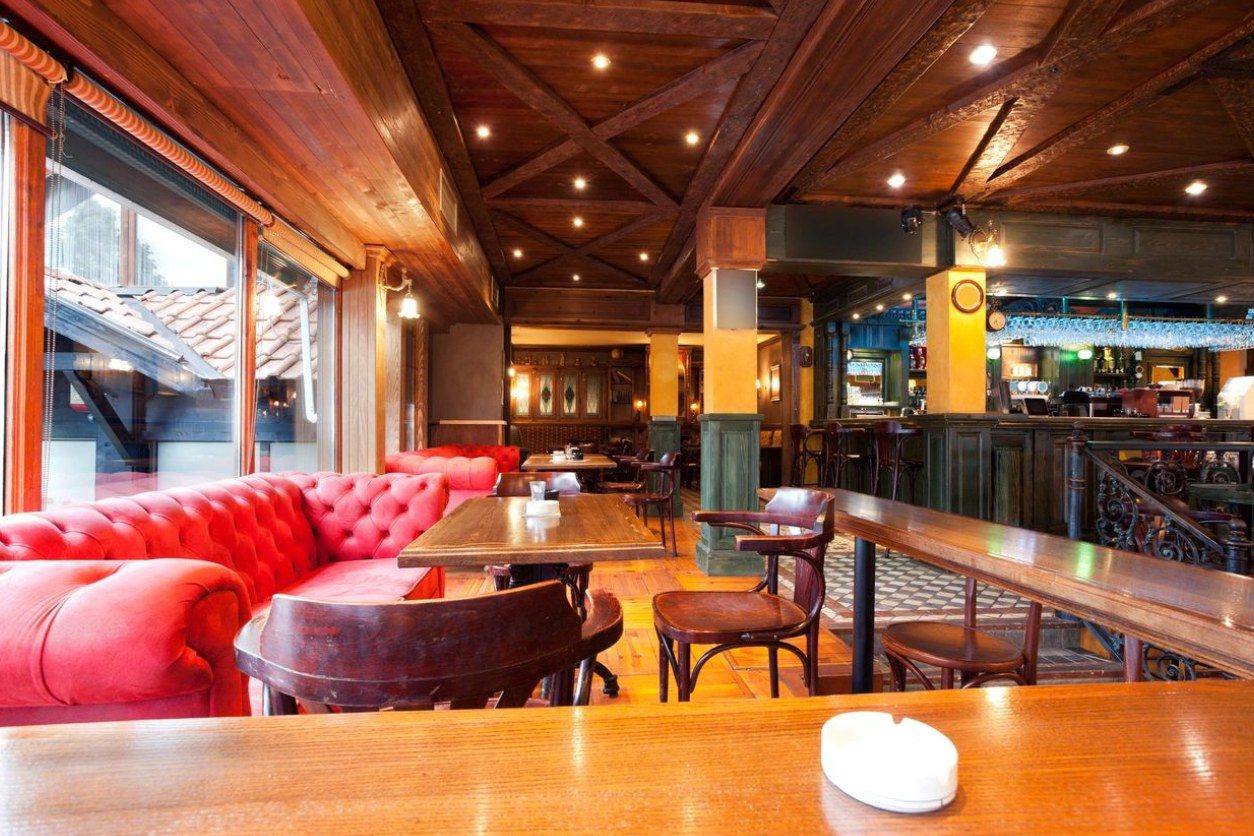 A restaurant with wooden tables and red couches.