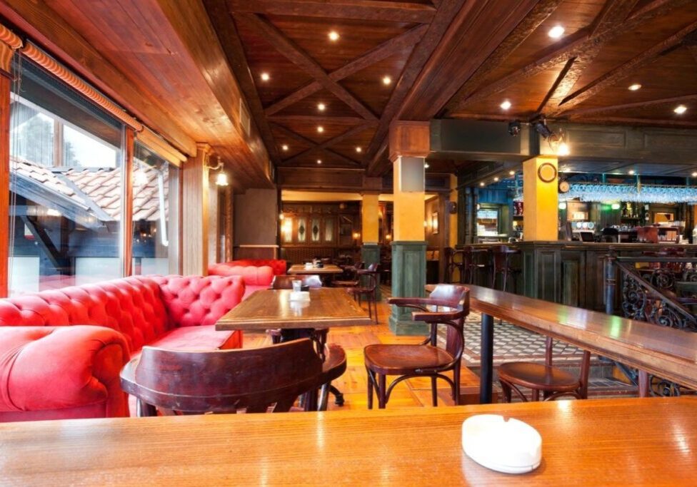 A restaurant with wooden tables and red couches.